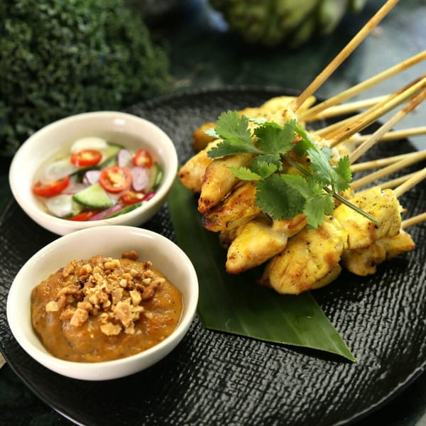 Laem Buri's chicken satay skewers with peanut sauce and cucumber relish on a black plate.