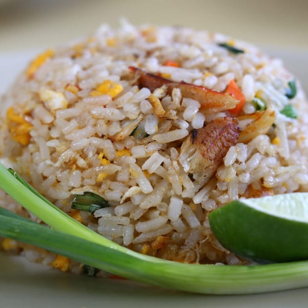 Close-up of Laem Buri's Thai fried rice with crab, egg, and vegetables, garnished with scallions and lime.