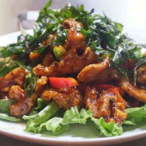 Laem Buri's Thai dish with crispy chicken, red peppers, and green herbs on lettuce.
